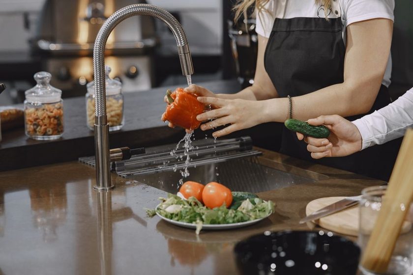 A bright kitchen counter with fresh produce, water, and a notebook
