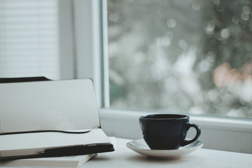 Soft morning light through a window with a mug and open notebook