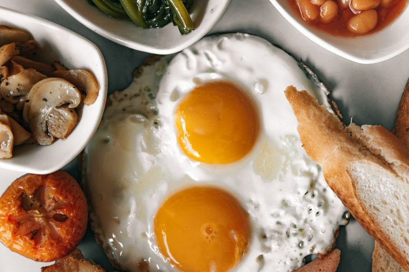 Plates of eggs, beans, fish and tofu arranged across a table