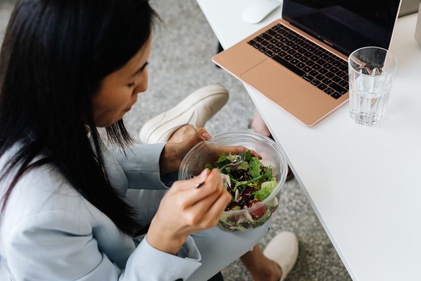 A bright desk by a window with a glass of water and a light lunch bowl